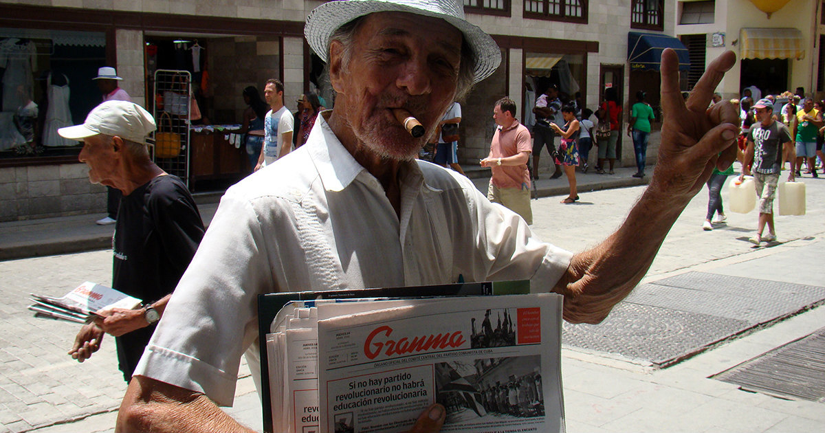 Un hombre posa junto al periódico Granma © CiberCuba