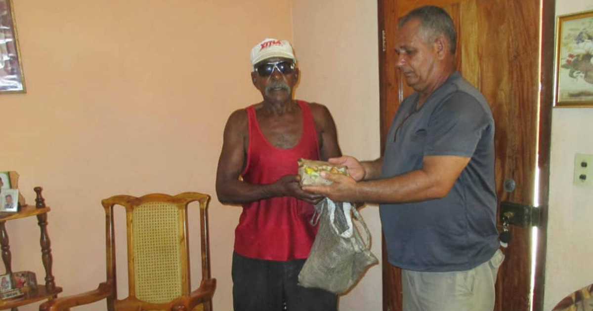 Uno de los integrantes del proyecto entrega una cajita de comida a un hombre © Facebook/Proyecto Capitán Tondique