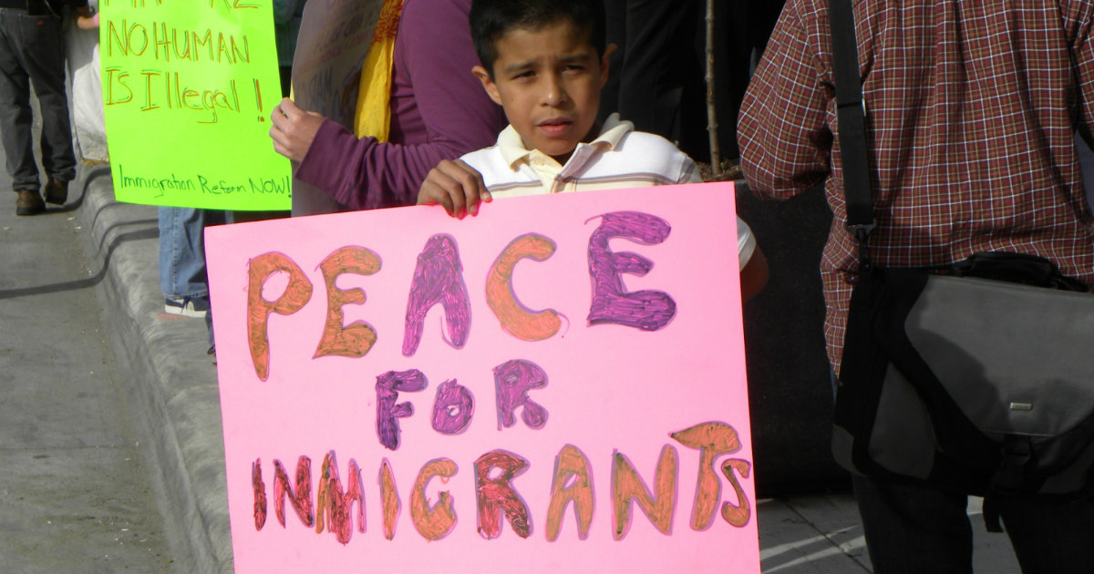 Niño inmigrante porta una pancarta © Flickr/Fibonacci Blue