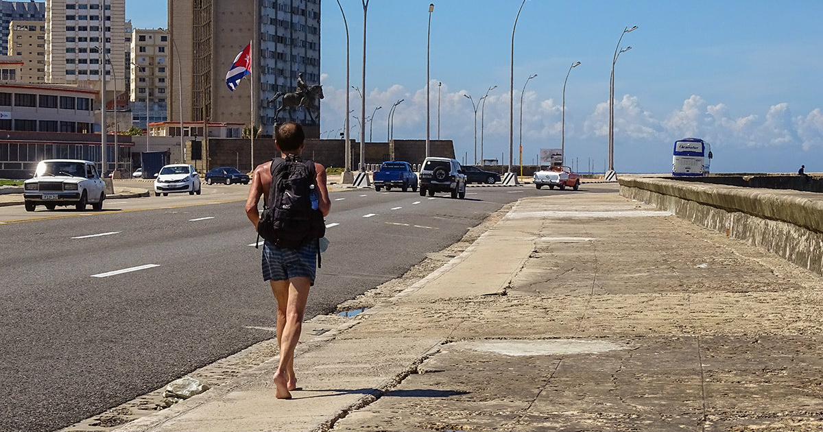 Un turista caminando descalzo por El Malecón © CiberCuba