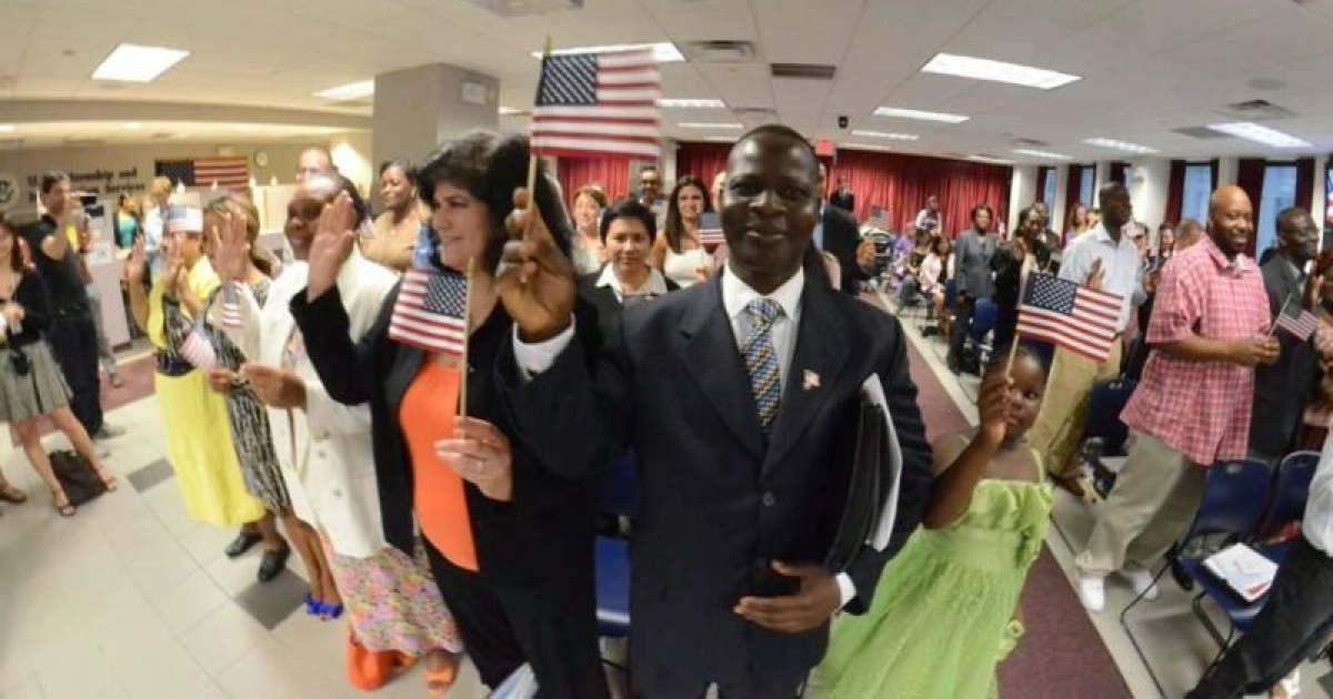 Migrantes posan mientras sostienen una pequeña bandera de Estados Unidos © Department of State
