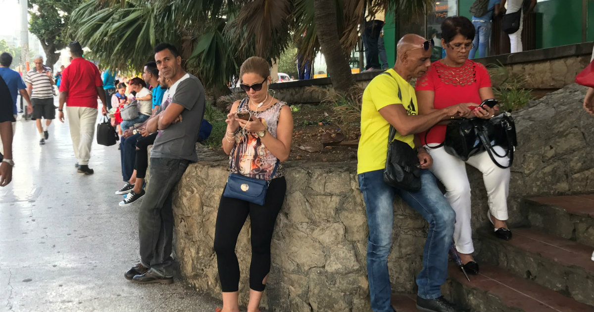 Ciudadanos cubanos revisan sus celulares en una zona wifi © CiberCuba