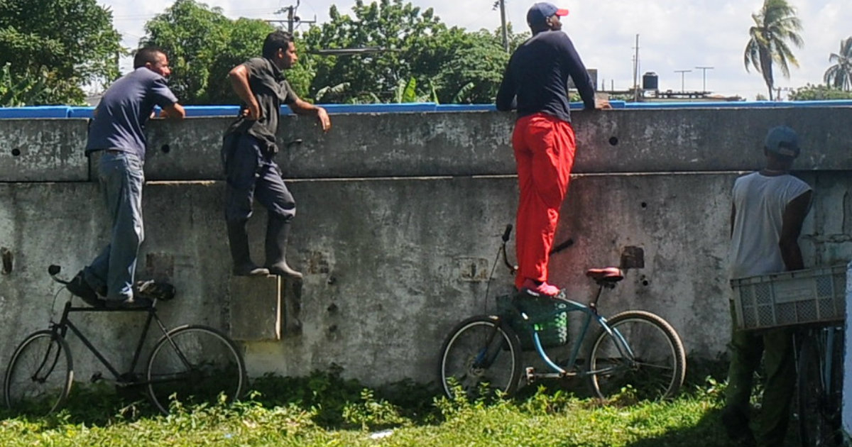 Cubanos ven la pelota sobre sus bicis, en el estadio Cristóbal Labra de la Isla de la Juventud. © Victoria.
