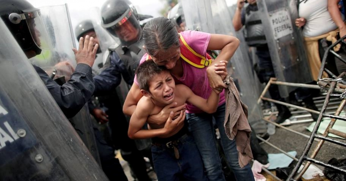 Mujer con su hijo tratando de cruzar la valla fronteriza. © Reforma Migratoria/ Facebook