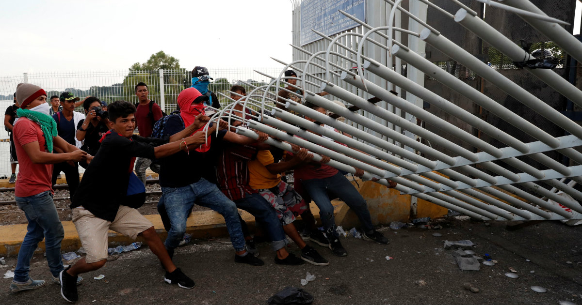Migrantes derriban la valla fronteriza que separa Guatemala y México © Reuters /Carlos Garcia Rawlins