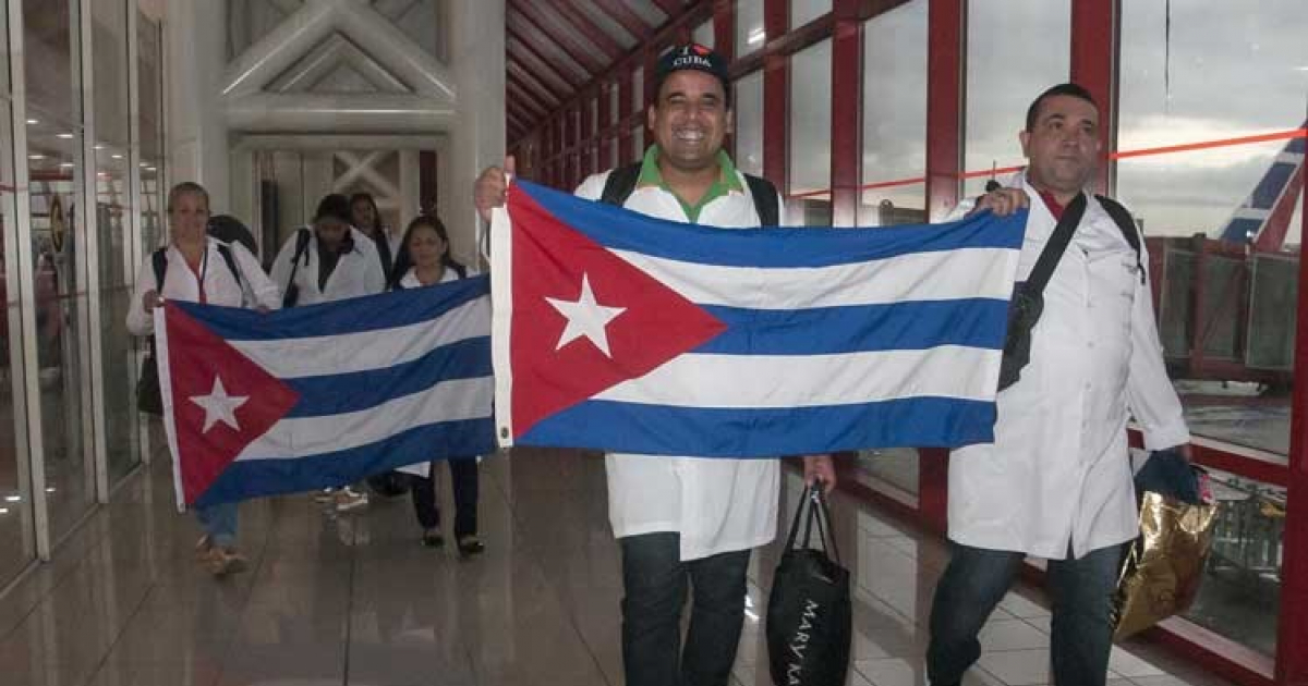 Médicos cubanos sujetan la bandera de Cuba a su llegada a la Isla © Prensa Latina