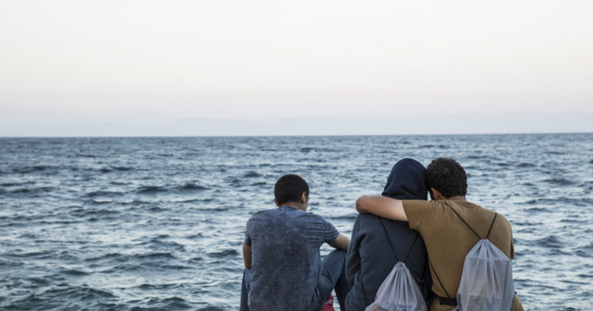 Migrantes se abrazan frente al mar. © Organización Internacional para las Migraciones / Amanda Nero