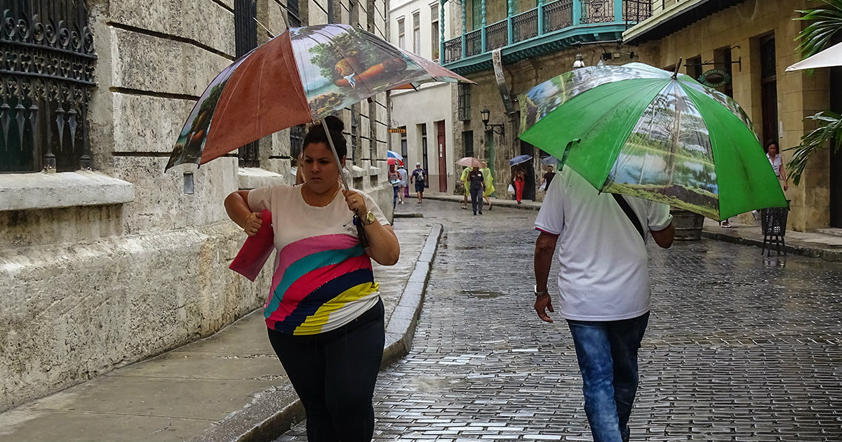 Dos personas caminan con paraguas por La Habana Vieja © CiberCuba