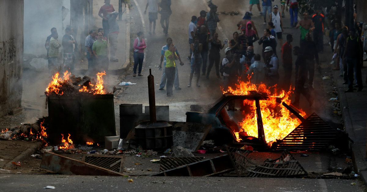 Manifestantes parados detrás de una barricada en llamas © Reuters / Carlos Garcia Rawlins