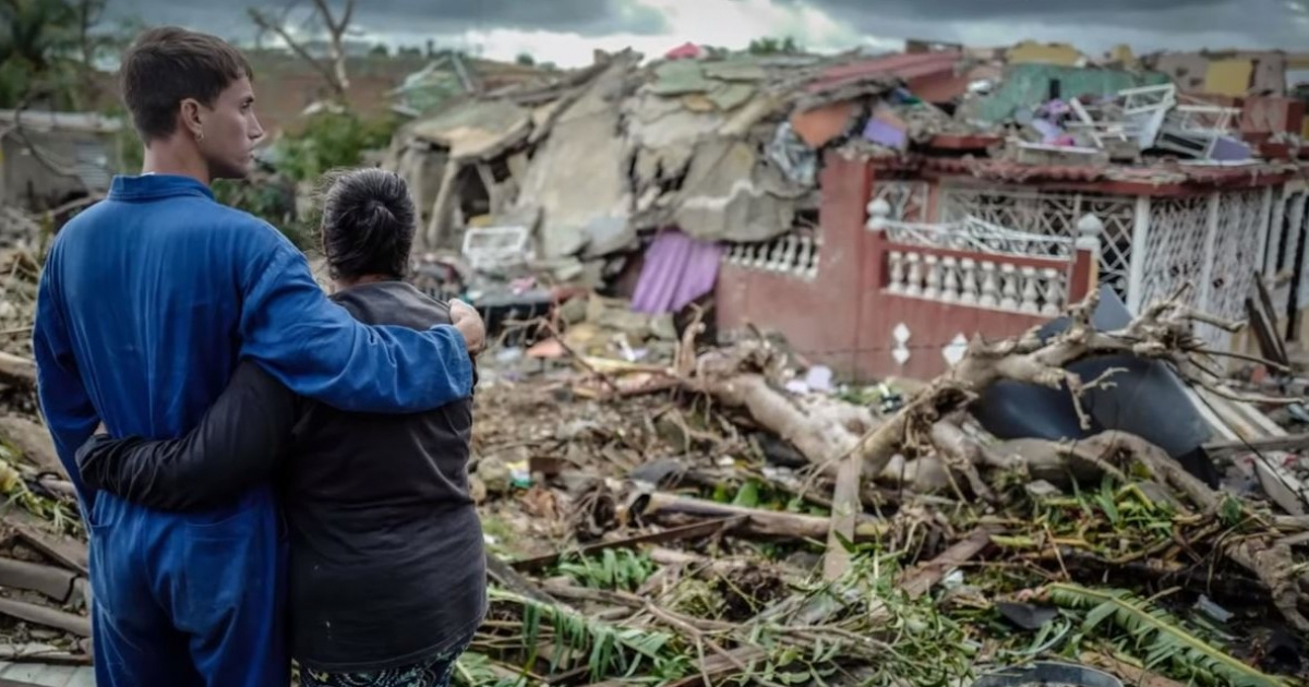 Dos cubanos se abrazan en medio de viviendas derruidas por el tornado © AFP