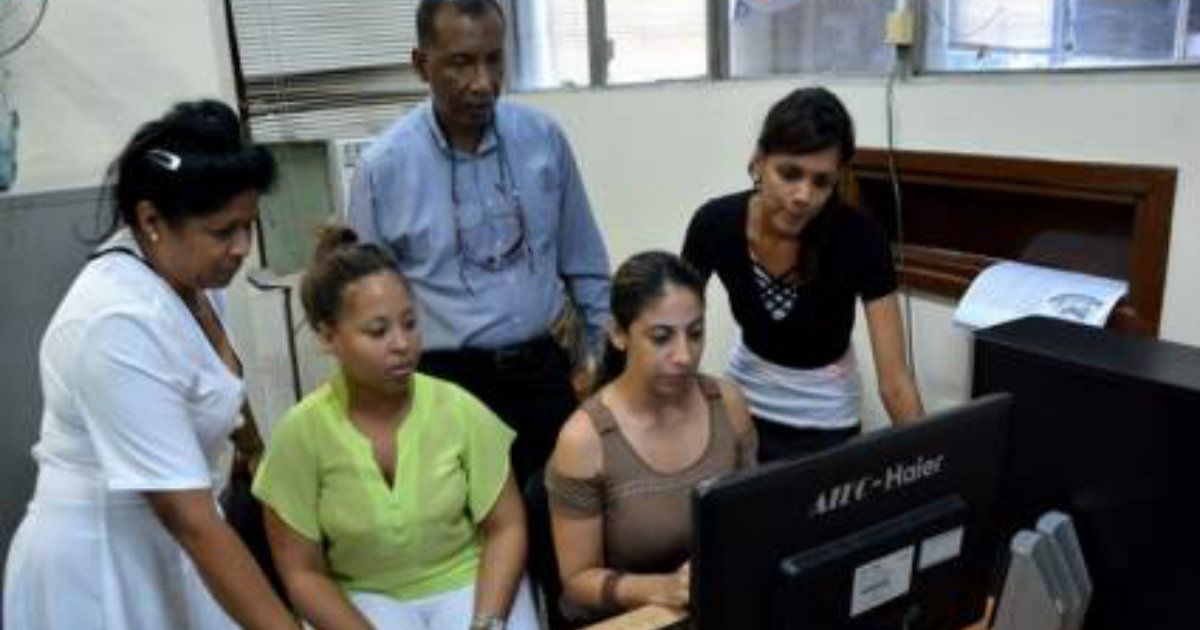 Varios trabajadores miran una sola computadora en un Registro en Cuba. © Juventud Rebelde