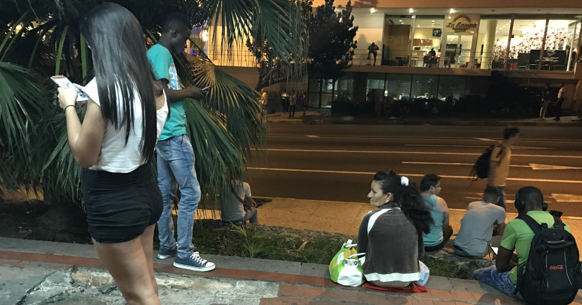 Cubanos, conectados a la zona Wifi, en la esquina de 23 y L. © CiberCuba.