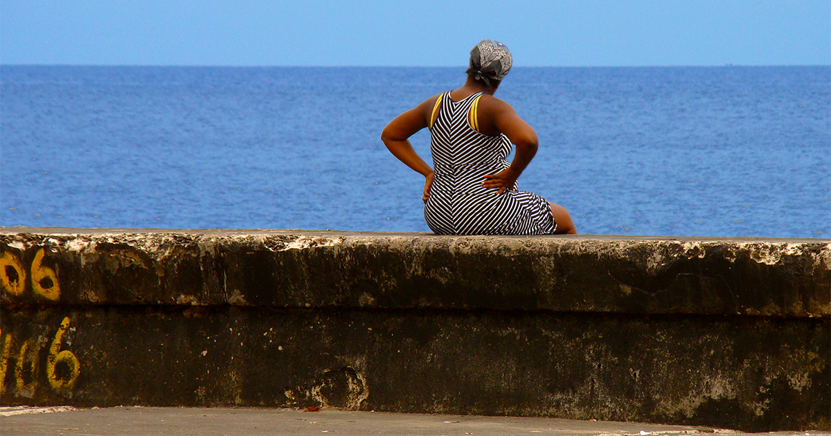 Mujer sentada en el muro del Malecón © CiberCuba