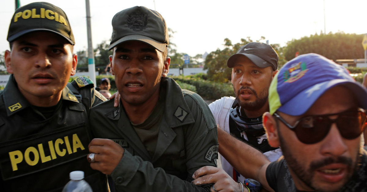 Miembro de la Guardia Nacional venezolana es acompañado por un policía colombiano © REUTERS/Marco Bello