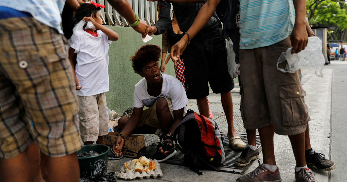 Jóvenes comen un pastel después de encontrarlo en una bolsa de basura en Caracas. © Reuters/ Carlos Jasso
