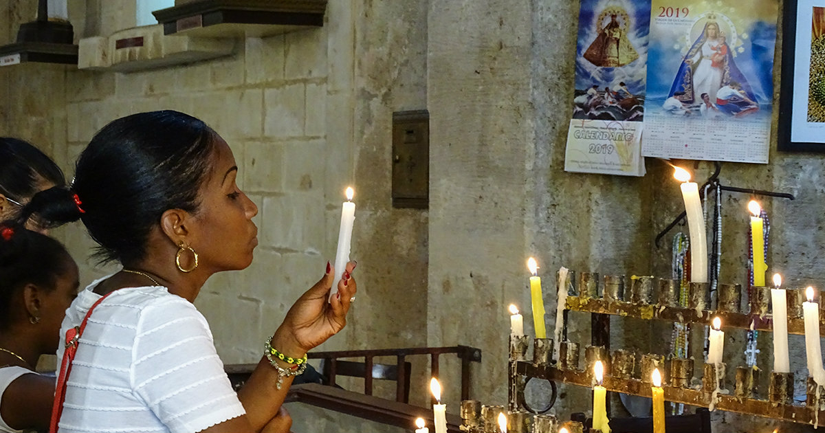 Mujer cubana con una vela encendida frente a un altar © CiberCuba