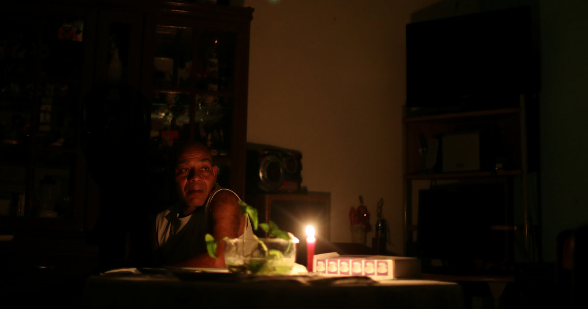 Un hombre se alumbra con una vela dentro de su casa durante un apagón en Caracas © REUTERS/Ivan Alvarado