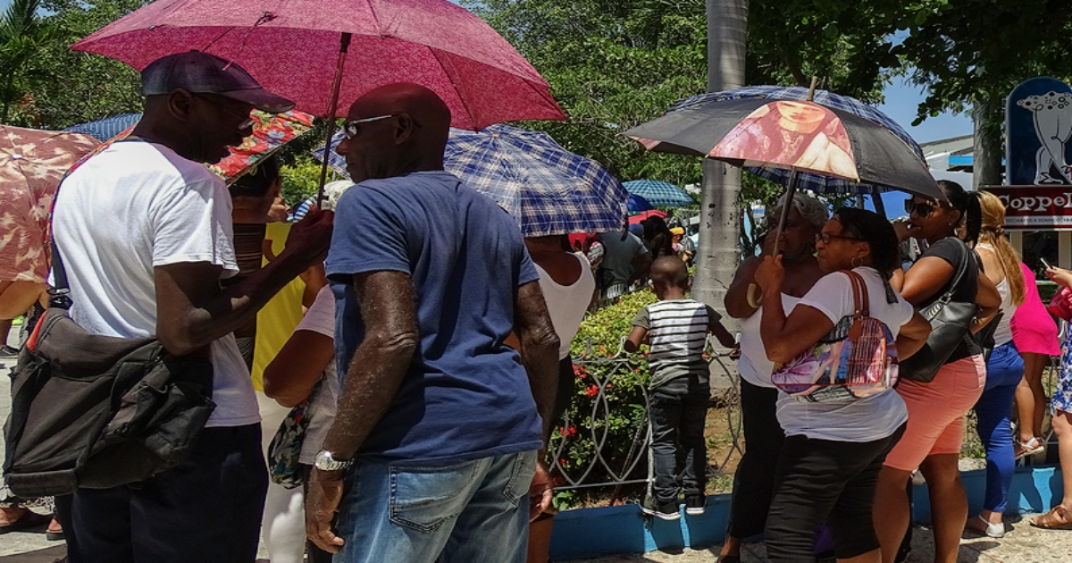 Cubanos con sombrillas en Coppelia para soportar el calor, imagen de referencia © CiberCuba