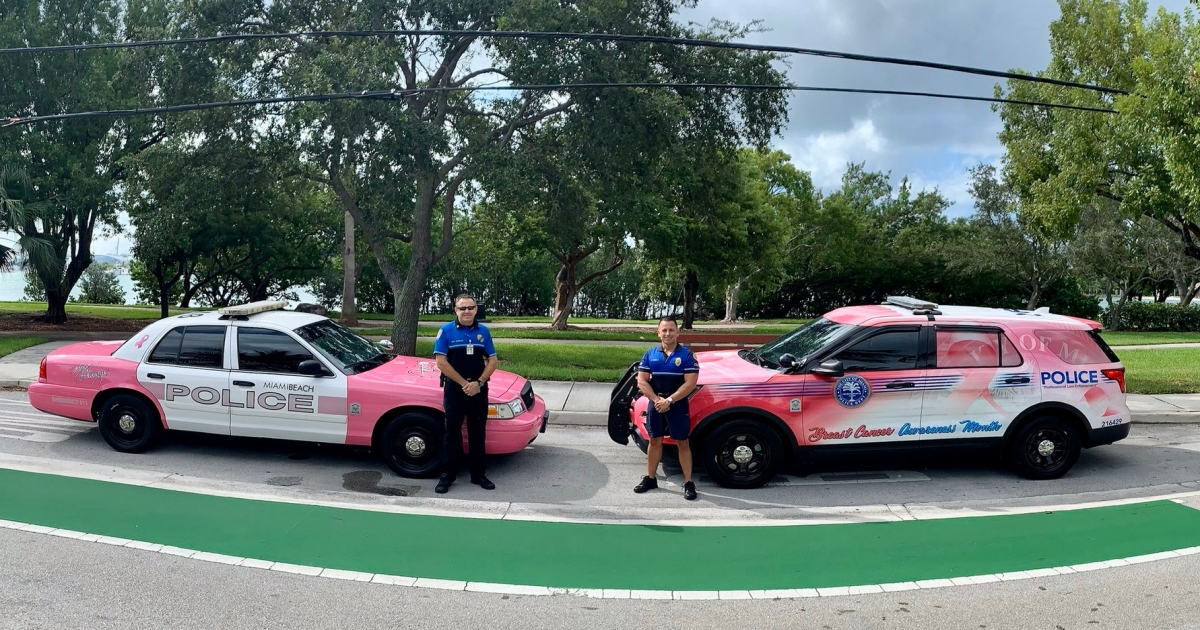 Agentes de la policía de Miami junto a patrullas pintadas de rosado © Twitter / Miami Beach PD