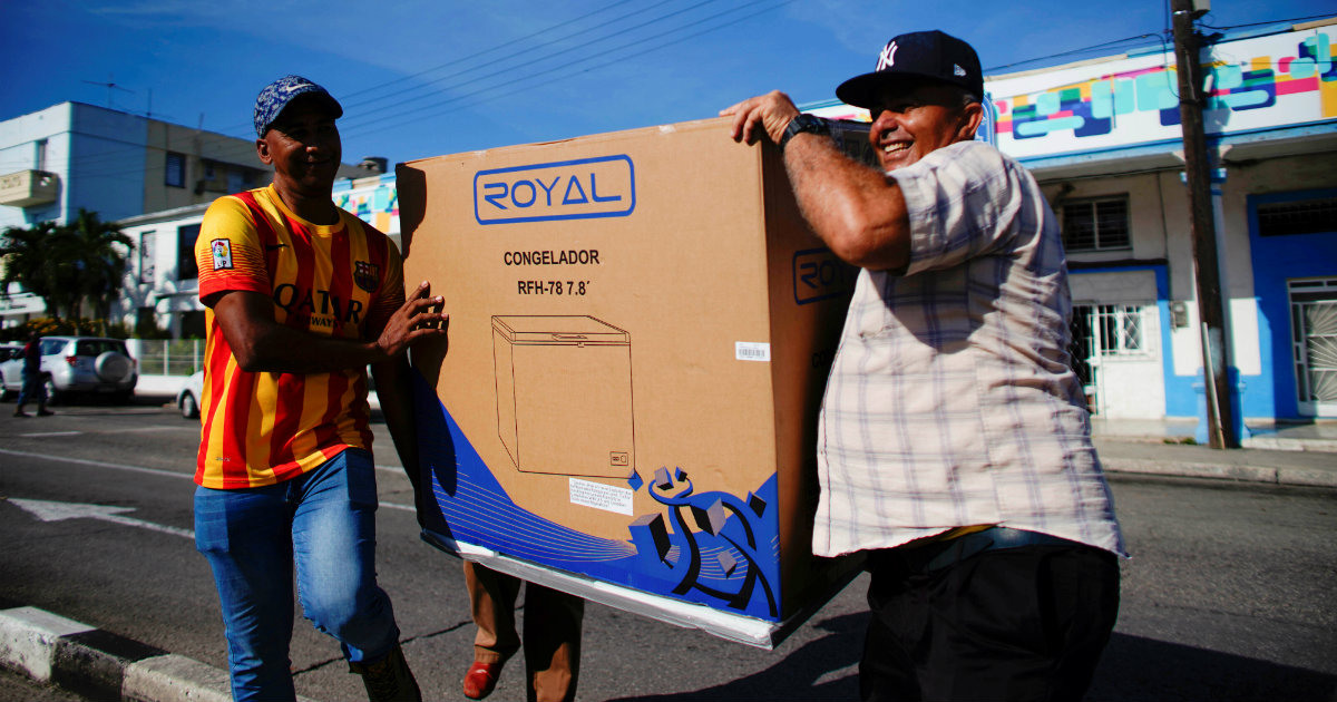 Cubanos llevan un congelador comprado en una tienda en divisa extranjera © Reuters / Alexandre Meneghini