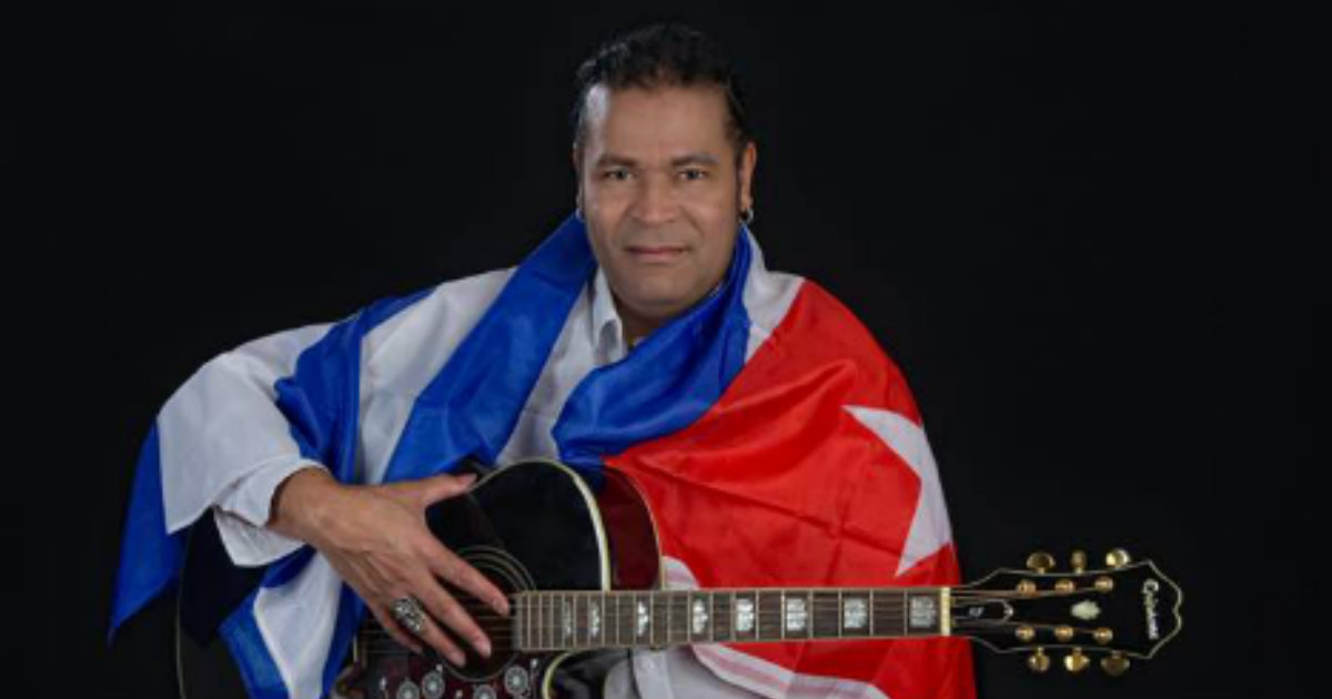 El cantautor Amaury Gutiérrez con la guitarra y la bandera de Cuba © Facebook / Amaury Gutiérrez
