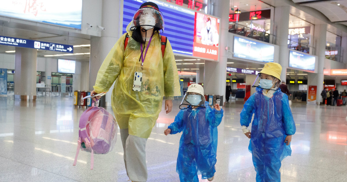 Pasajeros con máscaras faciales e impermeables en el Aeropuerto Internacional de Pekín © REUTERS/Thomas Peter