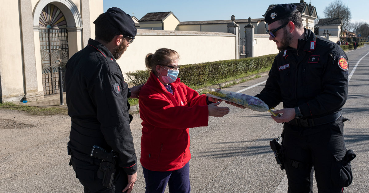 Los policías militares de Carabinieri hablan con una mujer que lleva una máscara protectora en el puesto de control en San Fiorano, el día 17 de cuarentena en una de las 11 pequeñas ciudades del norte de Italia que ha estado puesta en cuarentena desde febrero. © Marzio Toniolo/REUTERS