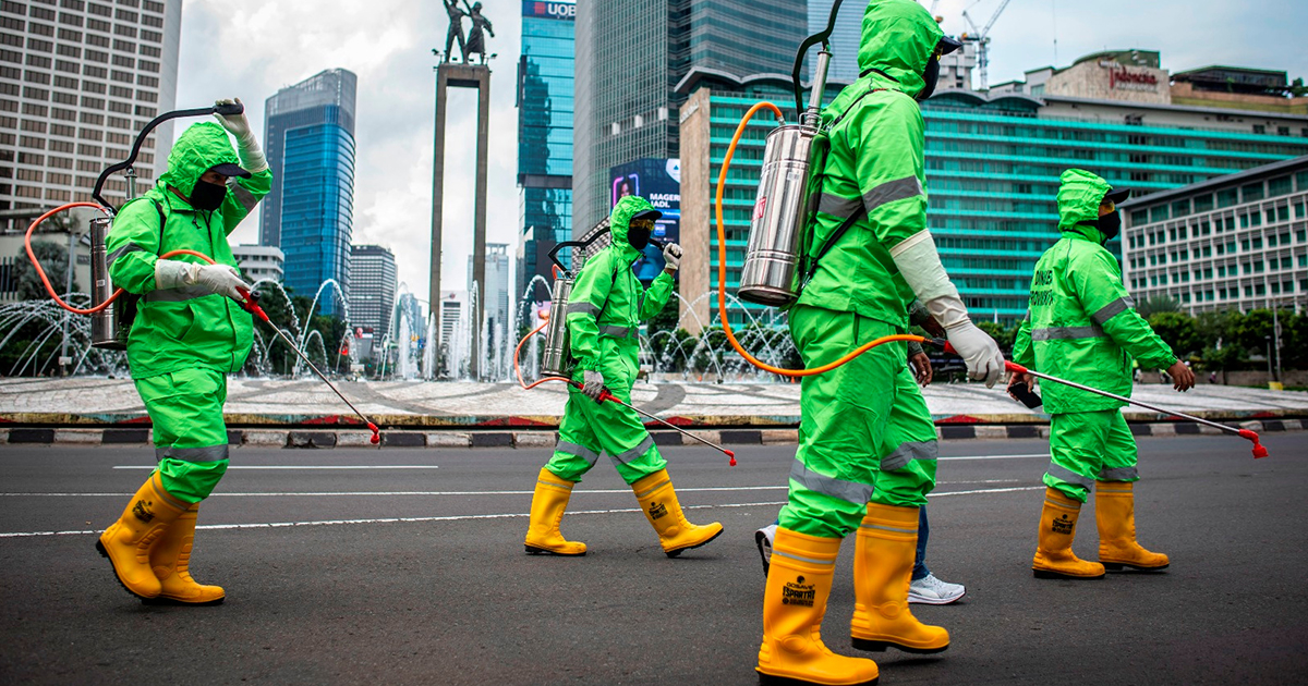 Trabajadores caminan en trajes protectores durante una operación de rociado de desinfectante en Yakarta © Foto/Aprillio Akbar/ vía REUTERS