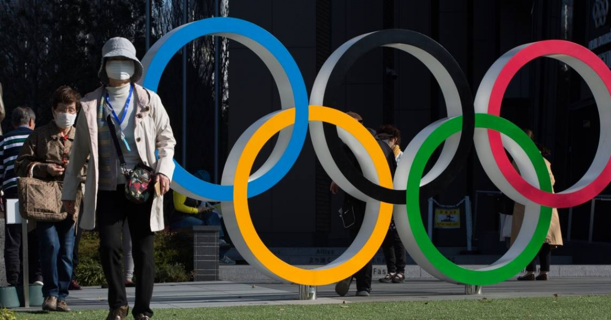 Personas caminando en Tokio con mascarillas junto al logo de los Juegos Olímpicos © Twitter/Noticias Nippon