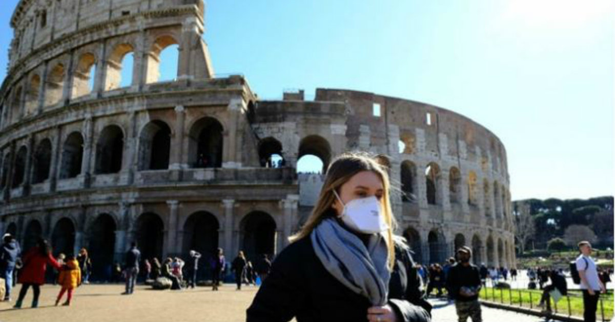 Una mujer con mascarilla camina junto al Coliseo, en Roma © YouTube/screenshot