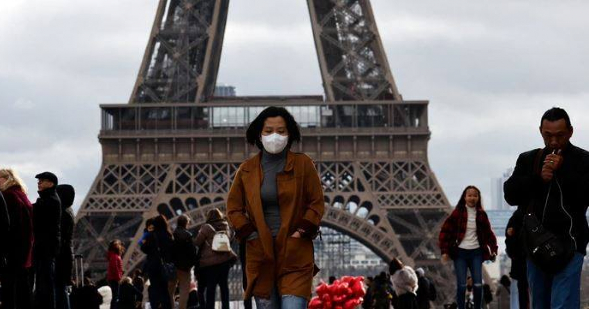 Una mujer se protege el rostro por temor a contagiarse de coronavirus frente a la Torre Eiffel en París, en febrero de 2020 © REUTERS / Gonzalo Fuentes