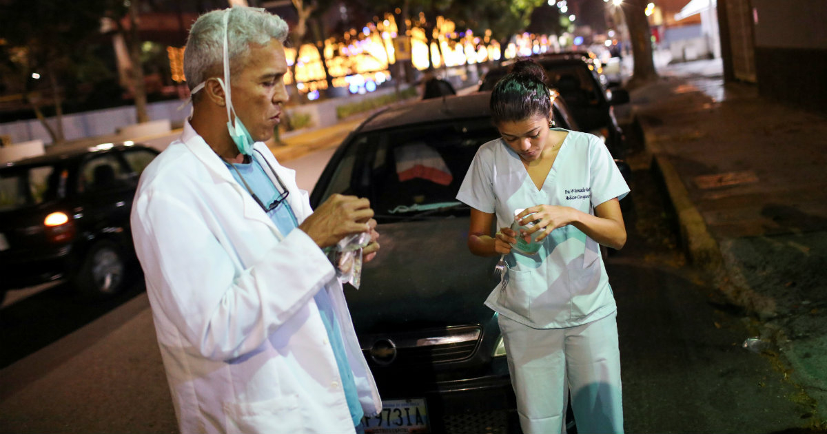 Dos médicos comen un refrigerio mientras esperan en una cola para comprar combustible en una estación de servicio, el 7 de abril © REUTERS / Manaure Quintero