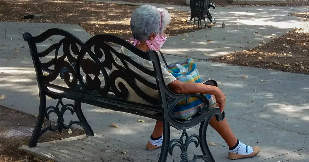 Anciana con un nasobuco sentada en un banco en Cuba © Cibercuba