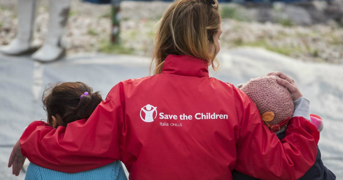Niños acompañados por una voluntaria de la organización Save The Children © SaveTheChildren