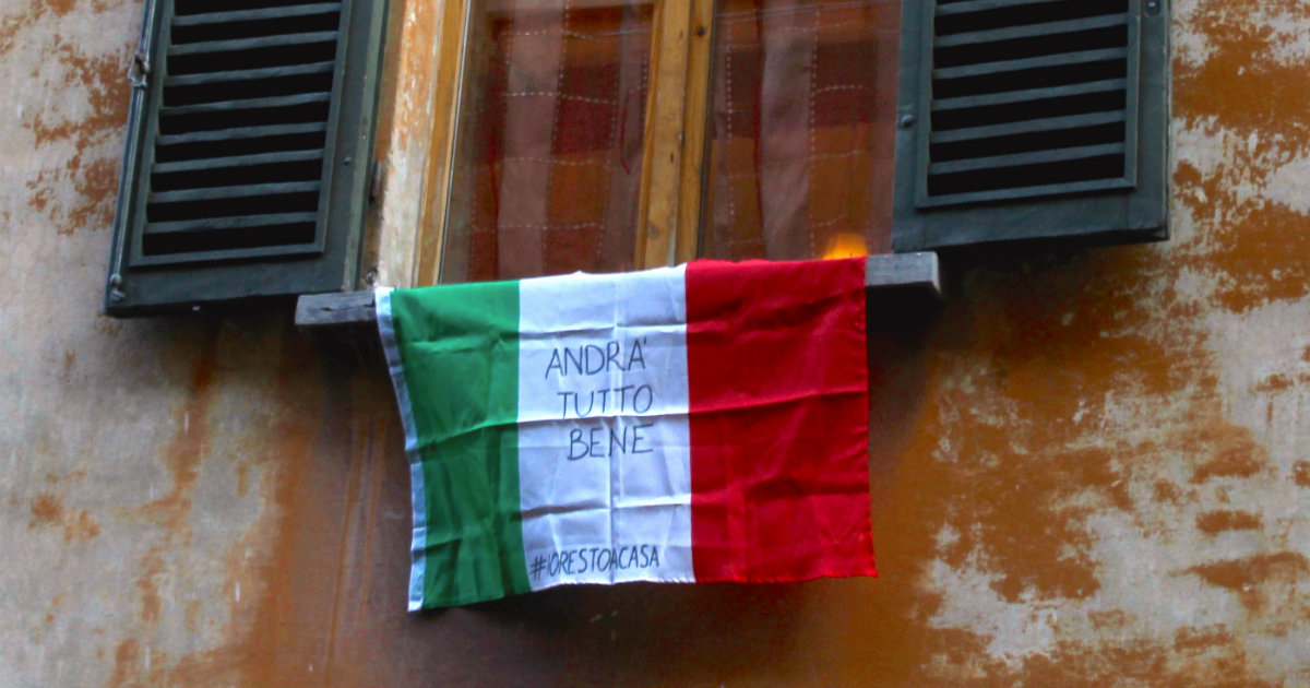 Bandera italiana cuelga de una fachada con el mensaje "Andará todo bien" © Wikipedia