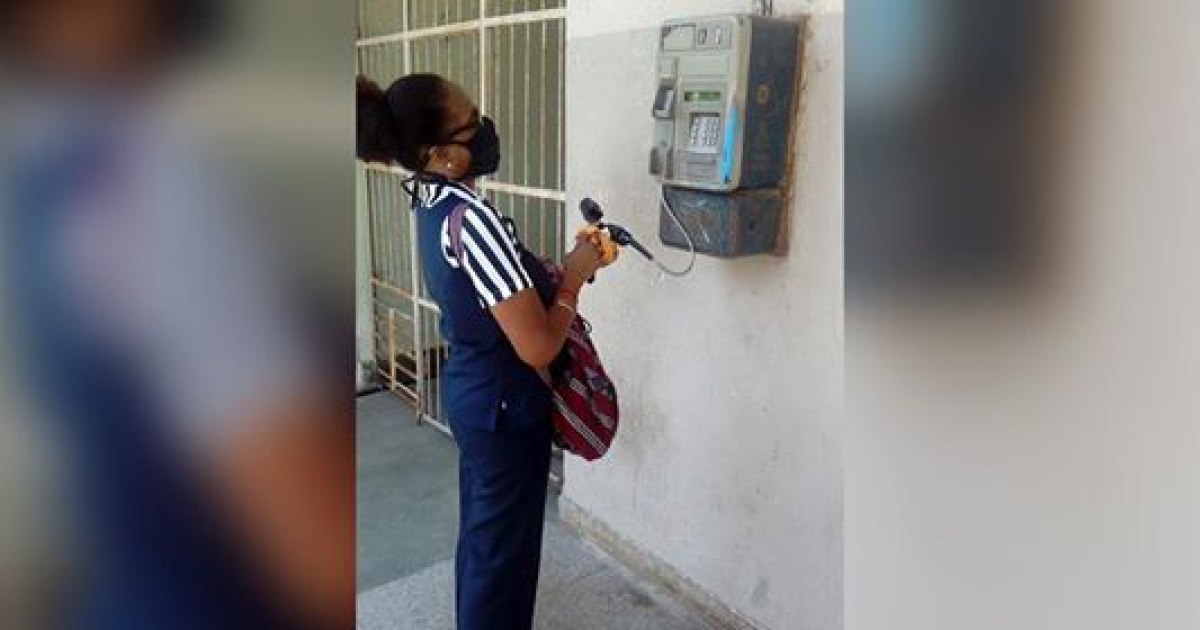 Trabajadora de ETECSA desinfectando un teléfono público en La Habana © CiberCuba