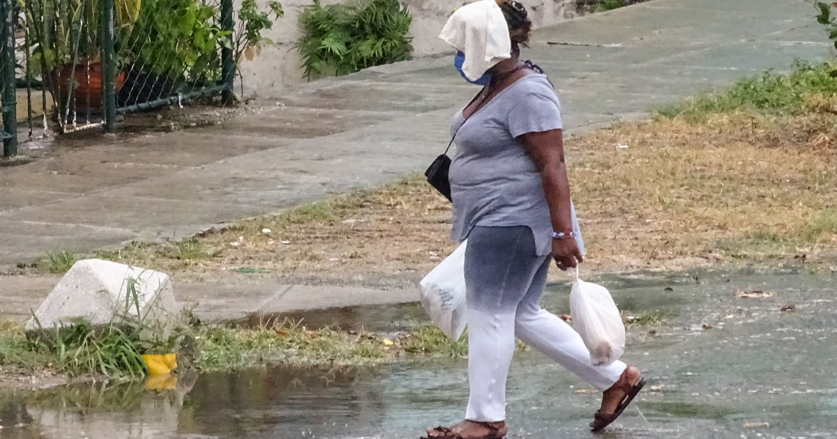 Cubana camina bajo la lluvia con mascarilla © CiberCuba 