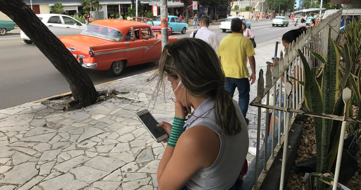 Cubana consulta su teléfono celular © CiberCuba