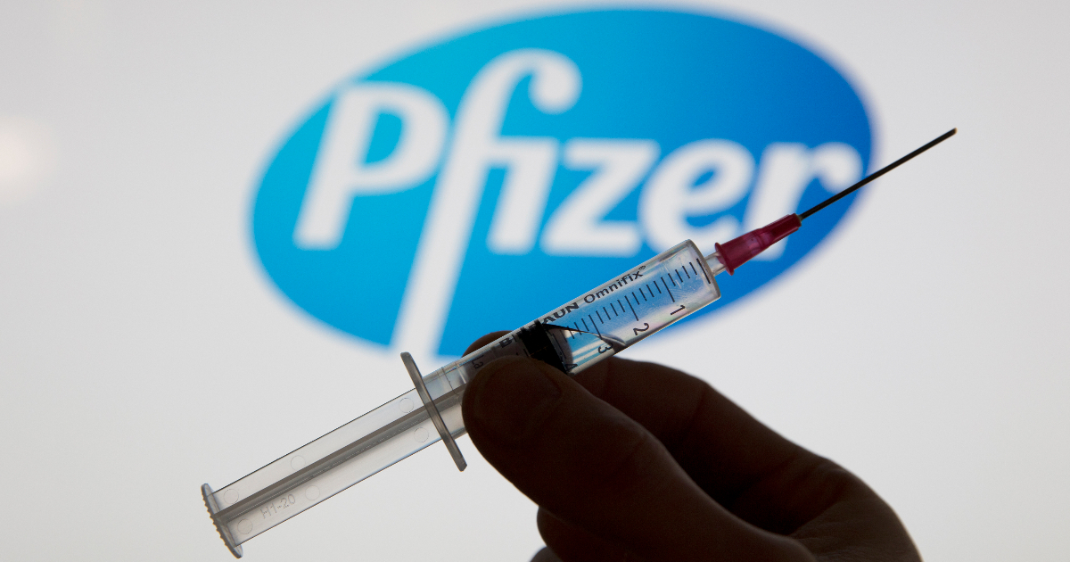 Una jeringa de vacuna covid frente al logotipo del Pfizer © <a href="https://sp.depositphotos.com/">Depositphotos</a>