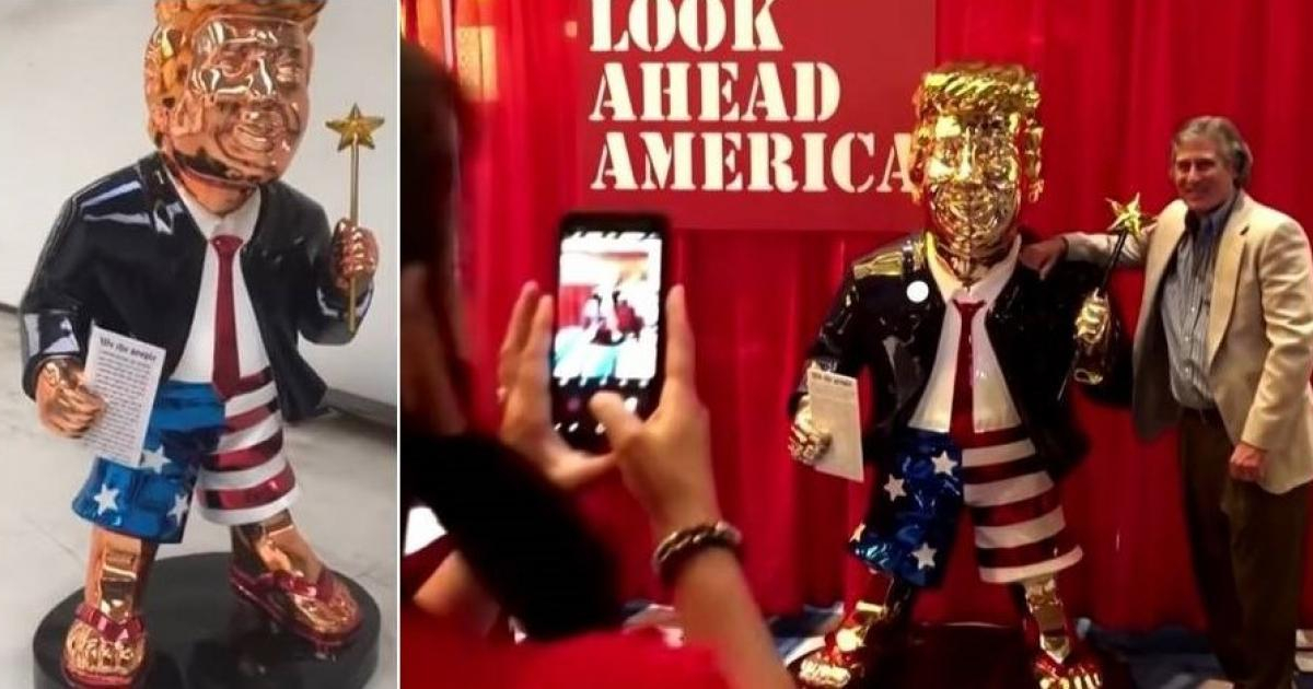 Estatua dorada de Trump y fanático del expresidente tomándose una foto © Captura de video de YouTube de Inside Edition y Reuters 
