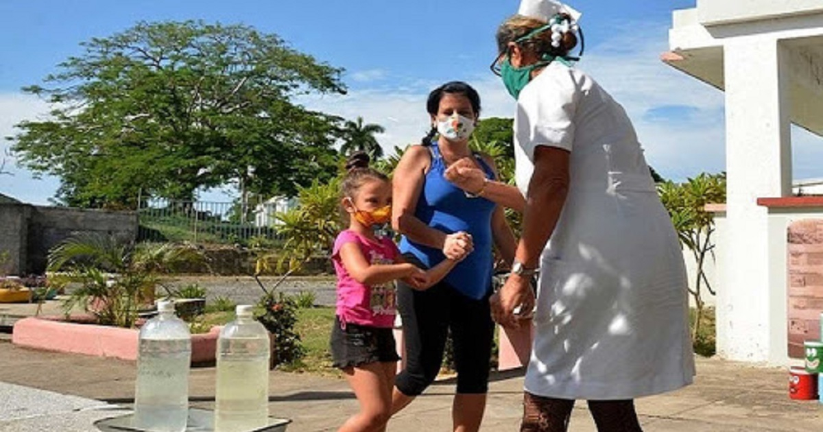 Enfermera aplicando solución clorada a la entrada de una institución en Cienfuegos. © Perla Visión
