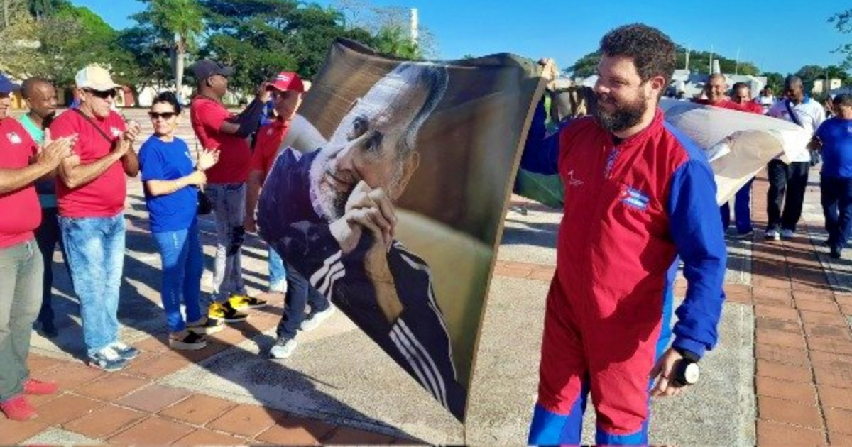 Nieto de Fidel Castro posa junto a una lona con la imagen de su abuelo con la que se lanzó en paracaídas © Twitter/JIT