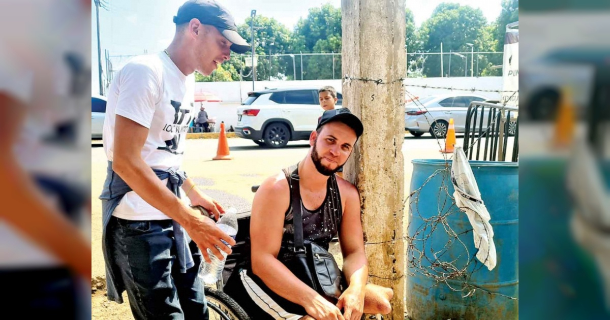 Joven migrante cubano en silla de ruedas junto al amigo que lo acompaña © Twitter/Excélsior