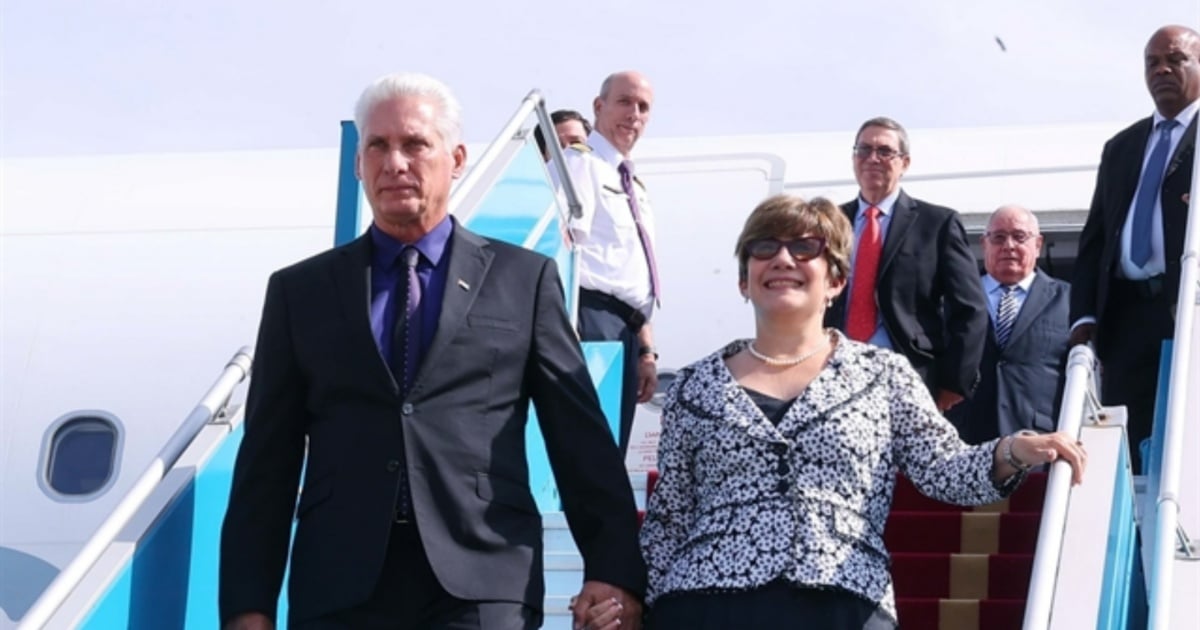 Fotografía conceptual y realista de Miguel Díaz-Canel y Lis Cuesta descendiendo de un avión privado en un aeropuerto de Vietnam, con elementos sutiles de la bandera cubana y vietnamita de fondo. Estilo cinematográfico, alta definición.