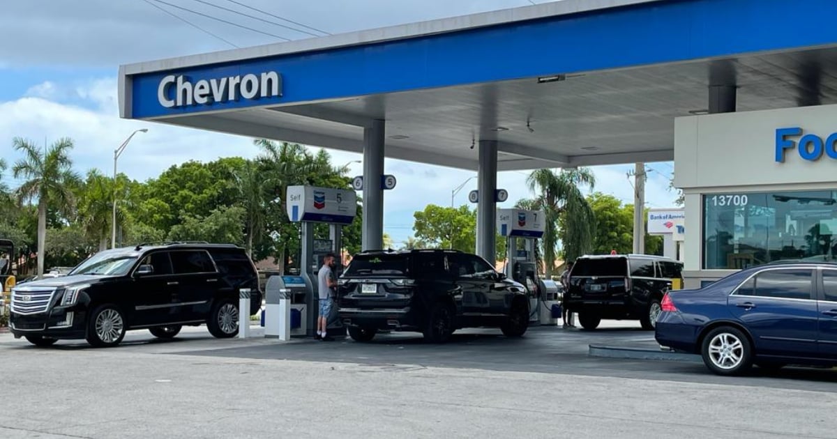 Fotografía conceptual y realista de una gasolinera moderna en Florida al atardecer, con precios digitales mostrando una disminución significativa. Estilo cinematográfico, alta definición.