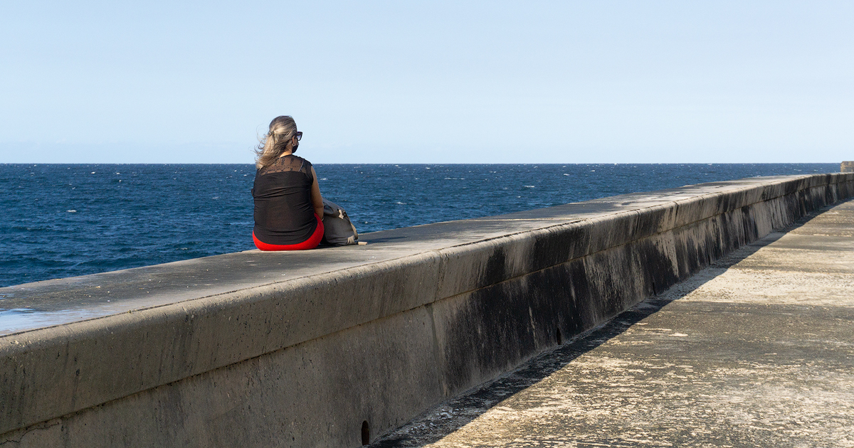 Cubana sentada en el muro del Malecón de La Habana. © CiberCuba