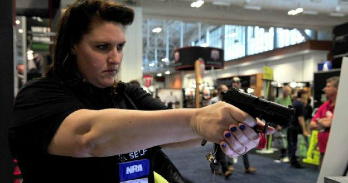 Mujer estadounidense apuntando con un arma de fuego © t13.cl