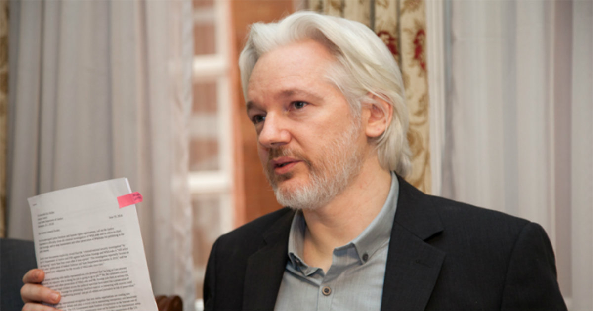 Julian Assange muestra una serie de papeles en la embajada de Ecuador en Londres © InfovisionRD