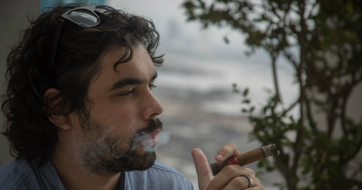 El cineasta cubano Carlos Lechuga conversando mientras fuma un puro © escritores.org