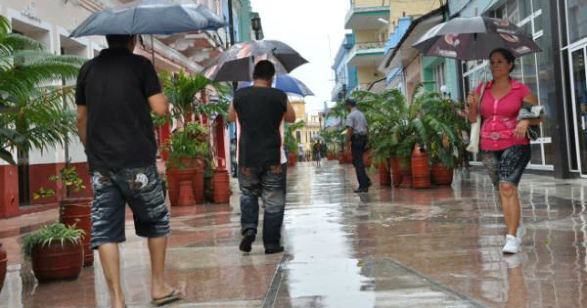 Habitantes de Cuba caminan con paraguas en un día de lluvia © Escambray